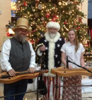 A picture of three people with dulcimers in front of a Christmas tree